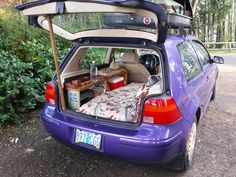 the back end of a purple car with its trunk open and it's bed pulled out