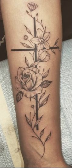 a cross and flowers tattoo on the leg