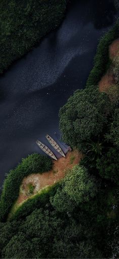 two canoes sitting on the shore of a river surrounded by lush green trees and bushes