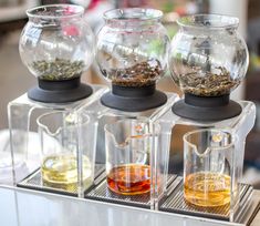 three glass teapots with different types of tea in them sitting on a table