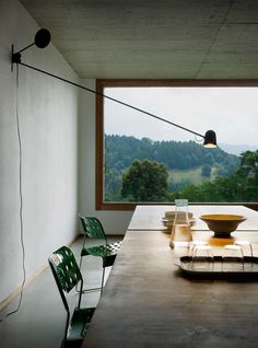 a long table with chairs and a bowl on it in front of a large window