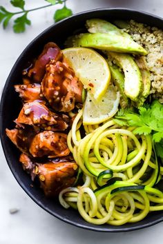 a bowl filled with chicken, zucchini noodles and couscous next to sliced cucumbers