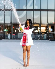 a woman standing in front of a building spraying water on her face