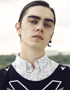 a young man with black and white shirt, earrings and piercings on his ears