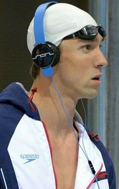 a man wearing headphones and swimming goggles on his face is looking off to the side