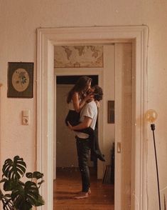 a man holding a woman in his arms while standing in front of a door way