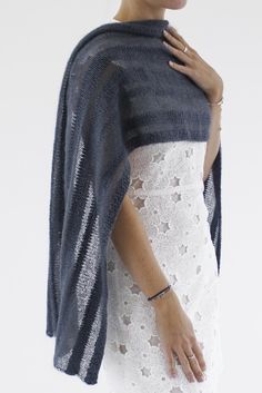 a woman wearing a white lace dress and a blue knitted shawl over her shoulders