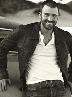 a black and white photo of a man in a leather jacket smiling at the camera