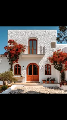 a white house with red flowers on the windows