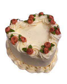 a heart shaped cake with white frosting and red roses