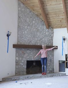 a woman standing in front of a stone fireplace with her arms out and hands outstretched