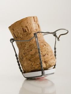 a close up of a wine cork in a metal holder on a white table top