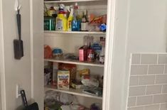 an open pantry door with lots of food and cleaning supplies in the bottom shelf area