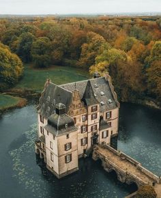 an aerial view of a castle in the middle of a lake with trees surrounding it