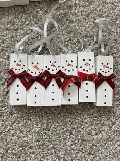 four snowmen with red and black bows on their heads are hanging from strings in the shape of dominos