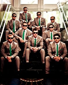 a group of men in suits and sunglasses sitting next to each other with their hands on their hips