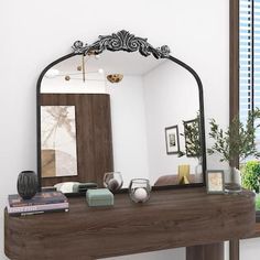 a mirror sitting on top of a wooden table in front of a window next to a potted plant