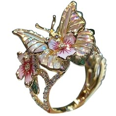 a close up of a ring with flowers and butterflies on the front, in gold tone