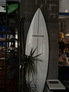 a white surfboard hanging up against a wall in a room with other items on display