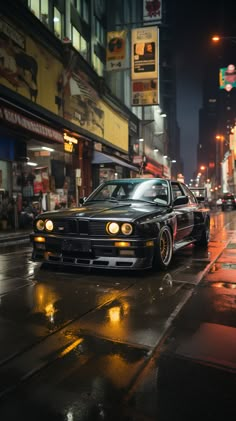 a black car parked on the side of a wet street in front of tall buildings