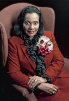 a woman in a red suit and flower on her lap