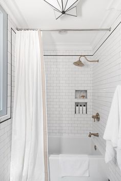 a bathroom with white tile and gold fixtures, including a shower curtain that is open to reveal the bathtub