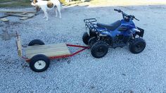 an atv pulling a trailer with a dog in the background