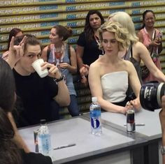 a woman sitting at a table in front of a group of people holding up cameras