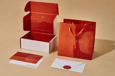 an open red gift bag sitting on top of a table next to two envelopes