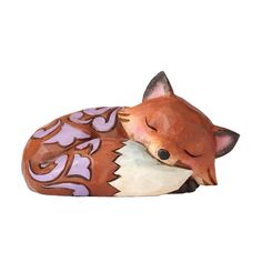 a ceramic figurine of a sleeping fox with purple accents on it's head