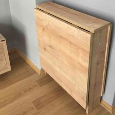 a wooden cabinet sitting on top of a hard wood floor next to a white wall