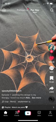 someone is drawing a spider web on the back of a t - shirt with an instagram sticker