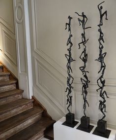 three sculptures on pedestals in the middle of a room with stairs leading up to them