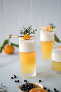 three glasses filled with drinks sitting on top of a table