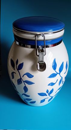 a blue and white jar with a lid on a blue surface next to a canister