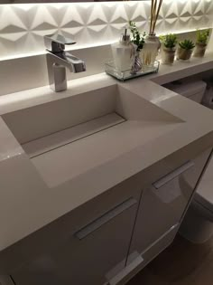 a bathroom sink sitting under a mirror next to a counter top with potted plants on it