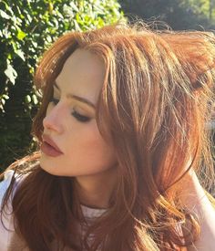 a close up of a person with long red hair and a cell phone in her hand