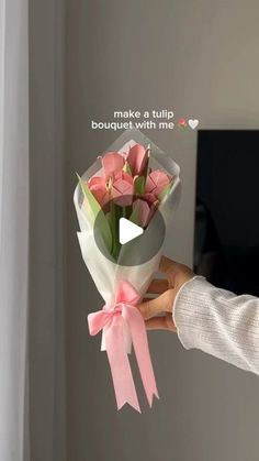 a woman holding a bouquet of pink tulips in front of a flat screen tv