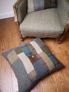 a chair and pillow on the floor in front of a couch with a plaid cushion