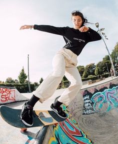 a young person riding a skateboard at a skate park with graffiti on the walls