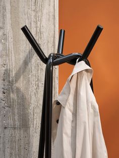 a coat rack with two coats hanging on it's sides next to a wall