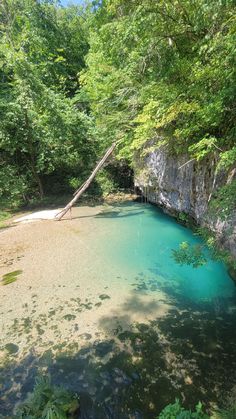 the blue pool is surrounded by trees and rocks, with water running down it's sides