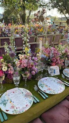 the table is set with flowers and place settings for guests to sit down at it