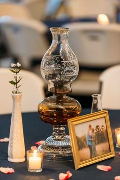 a table topped with vases filled with flowers and candles next to framed pictures on top of each other