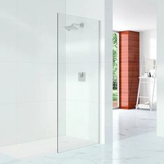 a bathroom with a walk in shower next to a white wall and tiled flooring