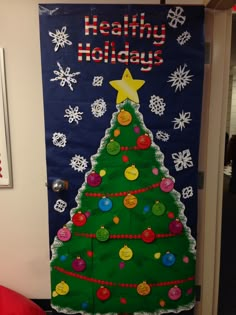 a door decorated with a christmas tree and holiday decorations on the front, in an office cubicle