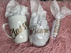 two coffee mugs sitting on top of a pink blanket next to one another with white tissue paper wrapped around them