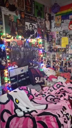 a bedroom decorated in pink and black with posters on the wall, bedding and lights