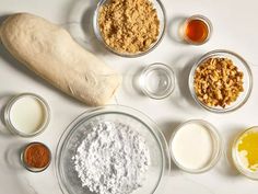 an assortment of ingredients are displayed on a white counter top, including flour, eggs, butter, and other items