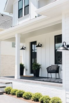 the front porch of a white house with black accents